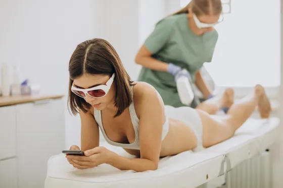 Clienta con gafas de protección durante una sesión de depilación láser en las piernas