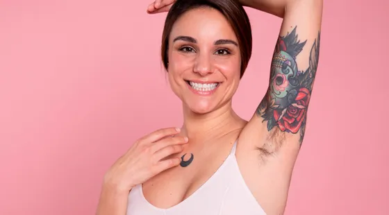 Mujer sonriente con un tatuaje en el brazo y vello en la axila